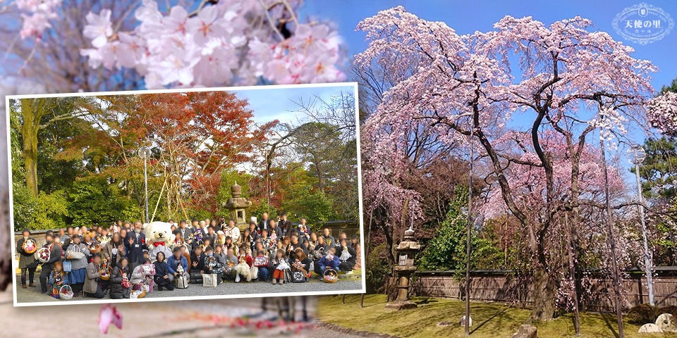 A group of attendees pose together for a photo in a garden surrounded by trees